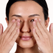 Close up of a woman applying Pepoxide concentrate around the eye area with fingertips