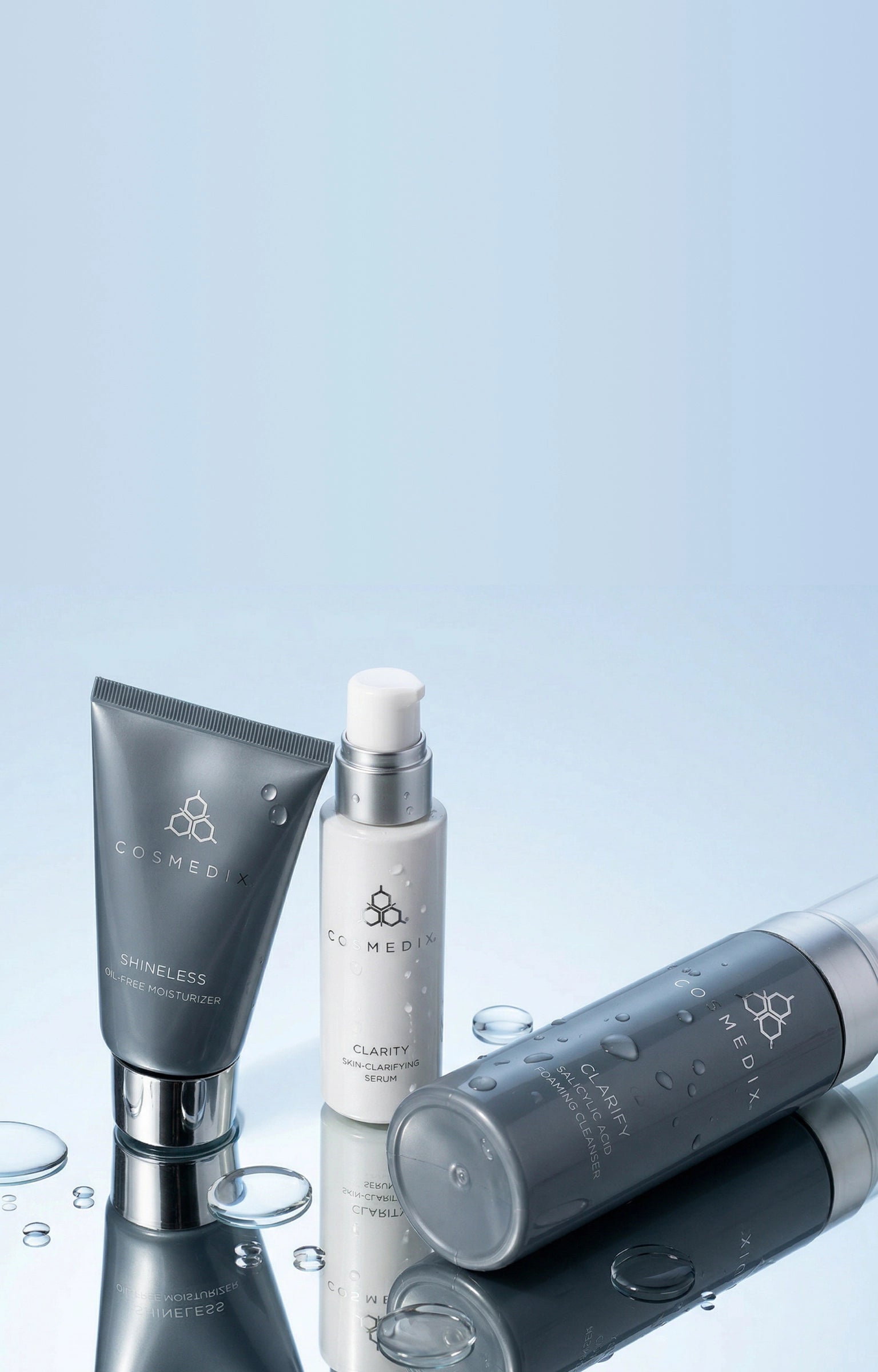 Shineless Moisturizer, Clarity Serum, and Clarify Cleanser displayed against a light blue background on a reflective surface. BREAKOUTS, REWRITTEN. 15% OFF ACNE ESSENTIALS. Cleanse, correct, and rebalance breakout-prone skin with a complete routine designed for visible results and long-term skin health.