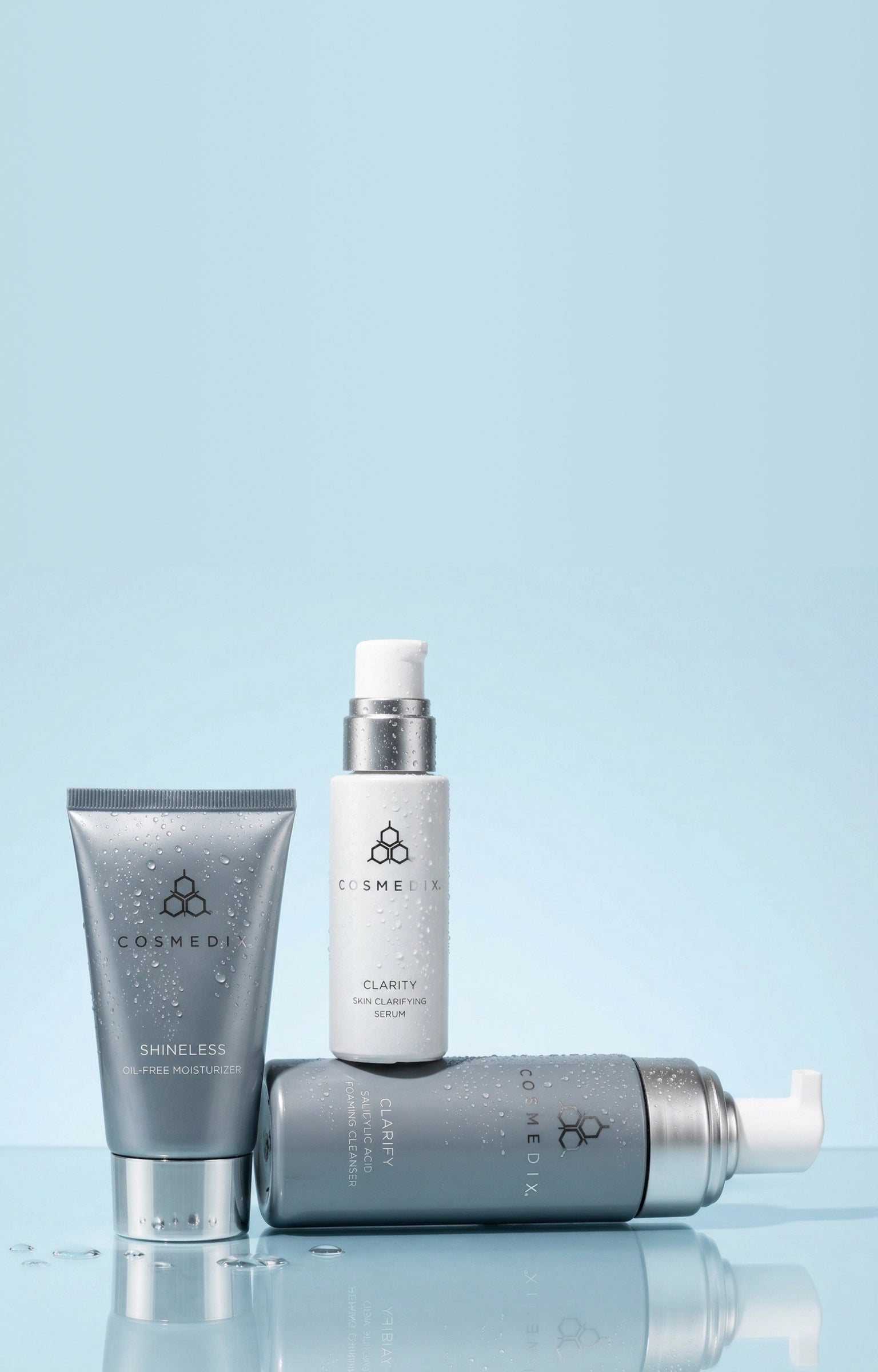 Shineless Moisturizer, Clarity Serum, and Clarify Cleanser displayed against a light blue background on a reflective surface. BREAKOUTS, REWRITTEN. 15% OFF ACNE ESSENTIALS. Cleanse, correct, and rebalance breakout-prone skin with a complete routine designed for visible results and long-term skin health.