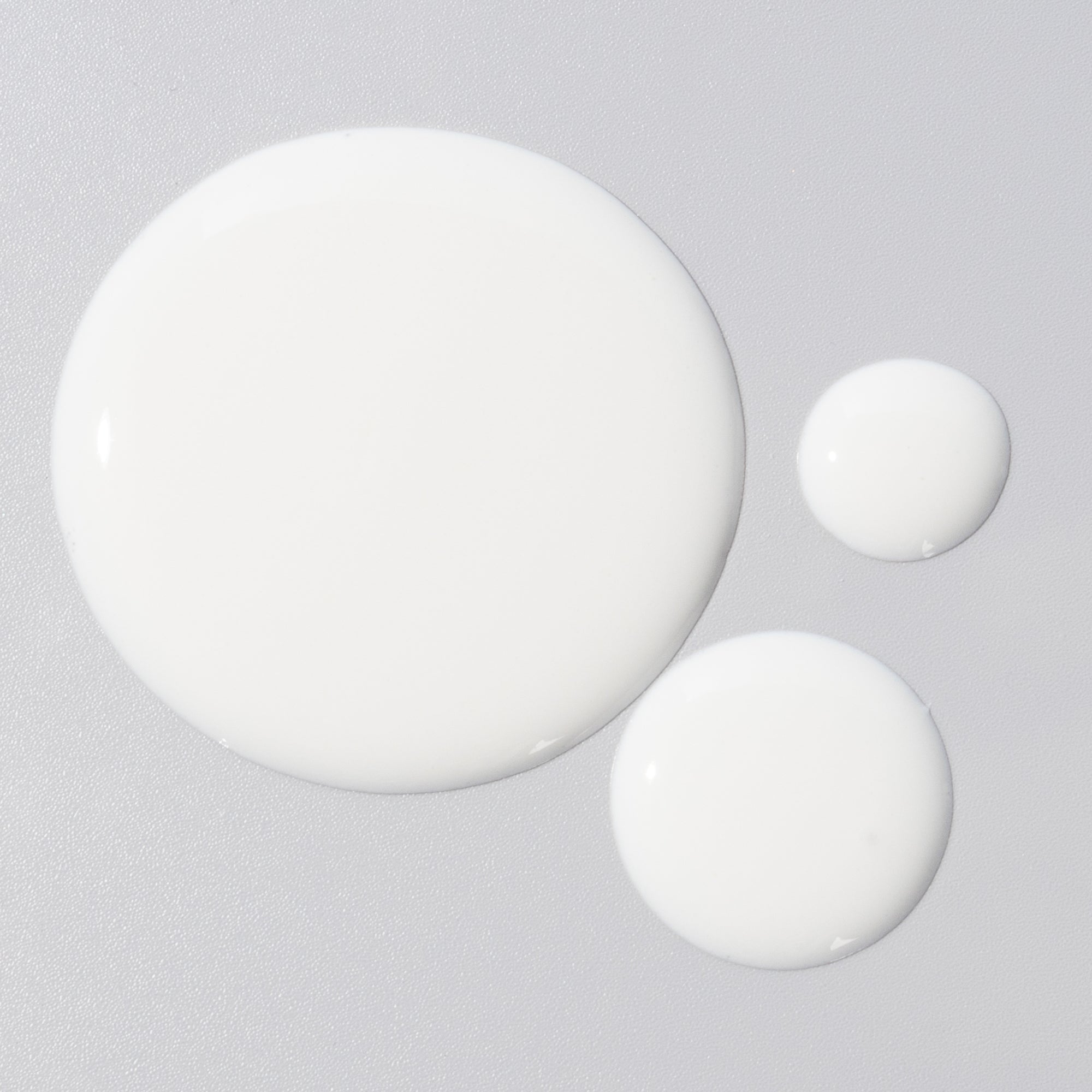 Close-up of white round sunscreen containers on a light gray textured background.